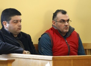Defendants Epaminondas Korkoneas and Vassilis Saraliotis wait for their trial to start inside a court hall in Amfissa town