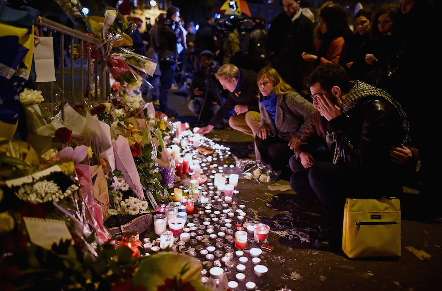 PARIS, FRANCE - NOVEMBER 14: People place flowers and candles on the pavement near the scene of yesterday's Bataclan Theatre terrorist attack on November 14, 2015 in Paris, France. At least 120 people have been killed and over 200 injured, 80 of which seriously, following a series of terrorist attacks in the French capital. (Photo by Jeff J Mitchell/Getty Images)